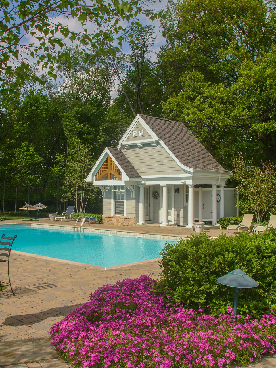Poolside estate landscape with paver terrace, lawn, planting, and outdoor-room context